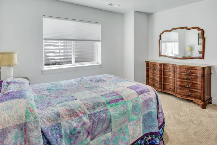 Carpeted interior space featuring a window with cellular shades, a white window frame, and neutral wall tones