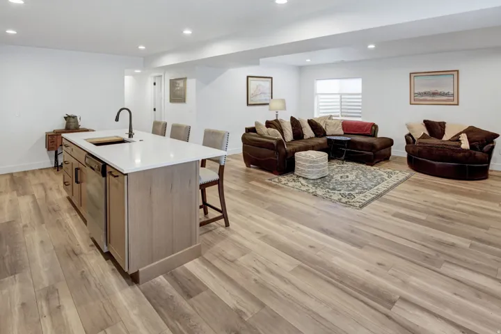 Open-concept living area featuring LVP flooring, recessed lighting, and a kitchen island with seating