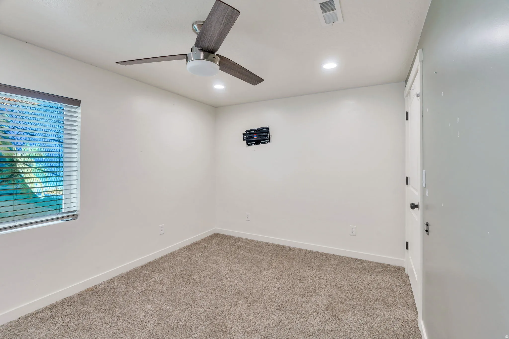 Room featuring carpet flooring, white walls, and a window with horizontal blinds