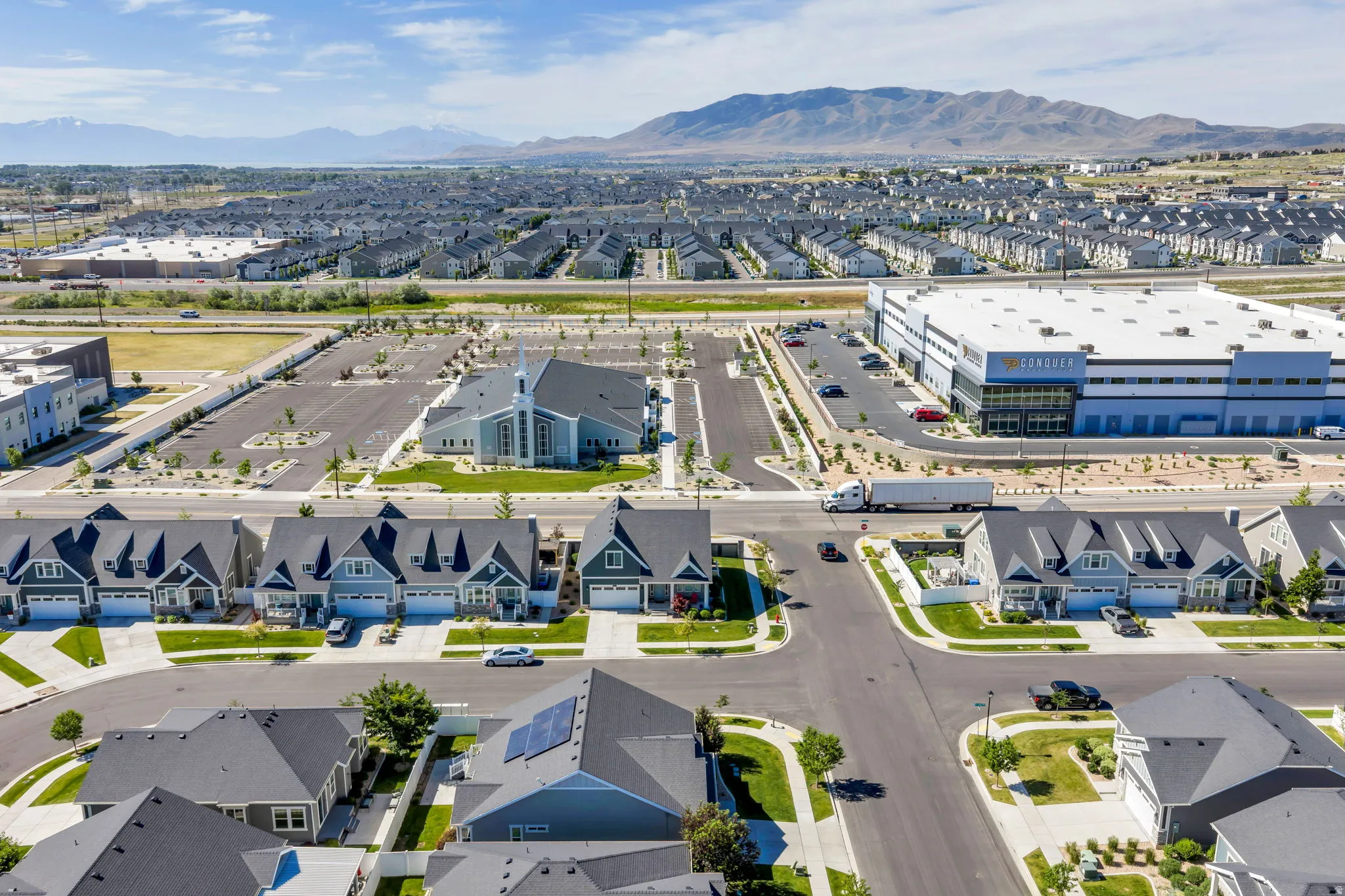 Expansive community showcasing residential properties, a commercial building with visible branding, a church with a steeple, and mountain scenery in the distance