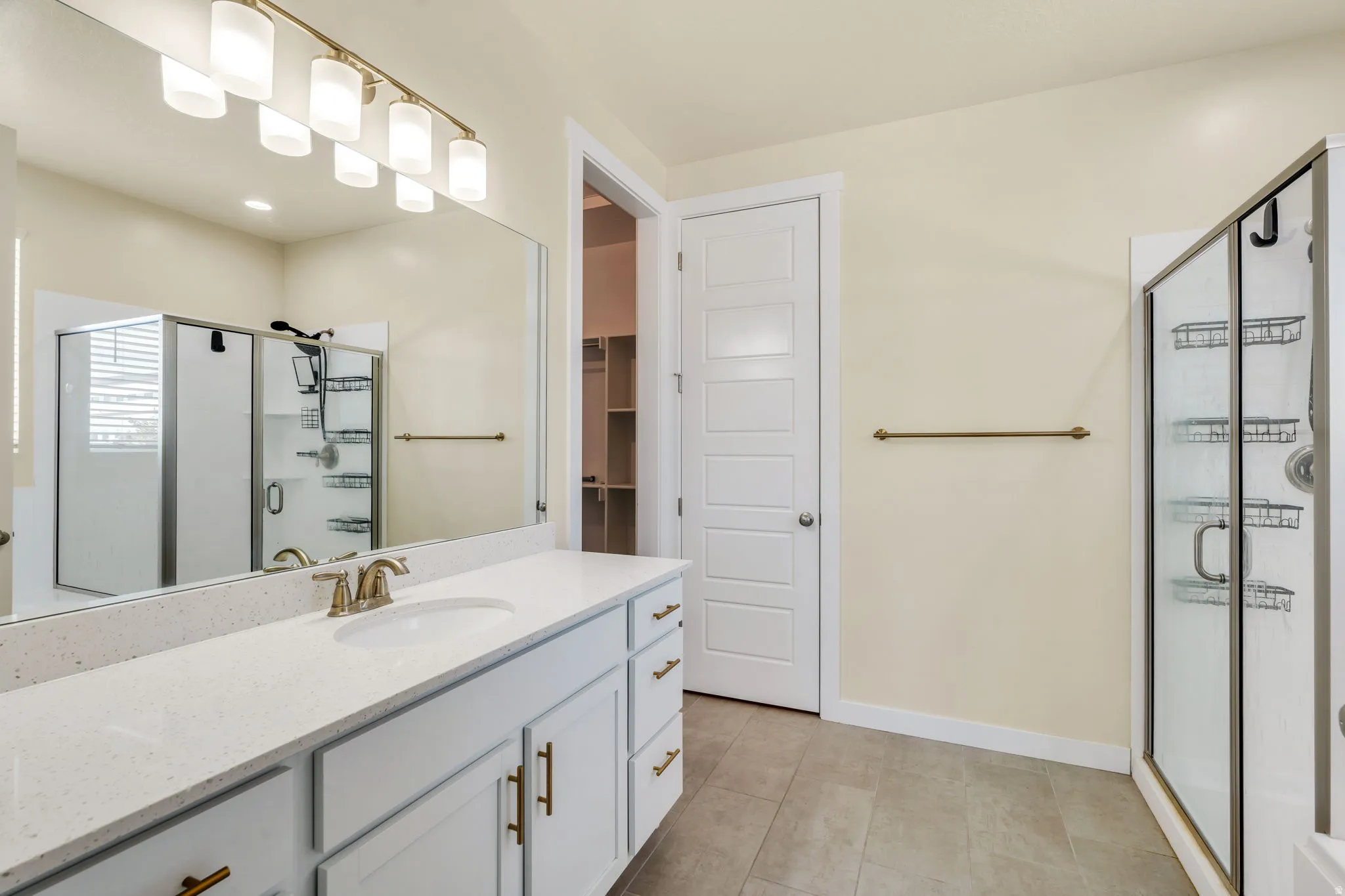 Dual-sink vanity with a light-toned countertop, brushed brass fixtures, and white cabinetry