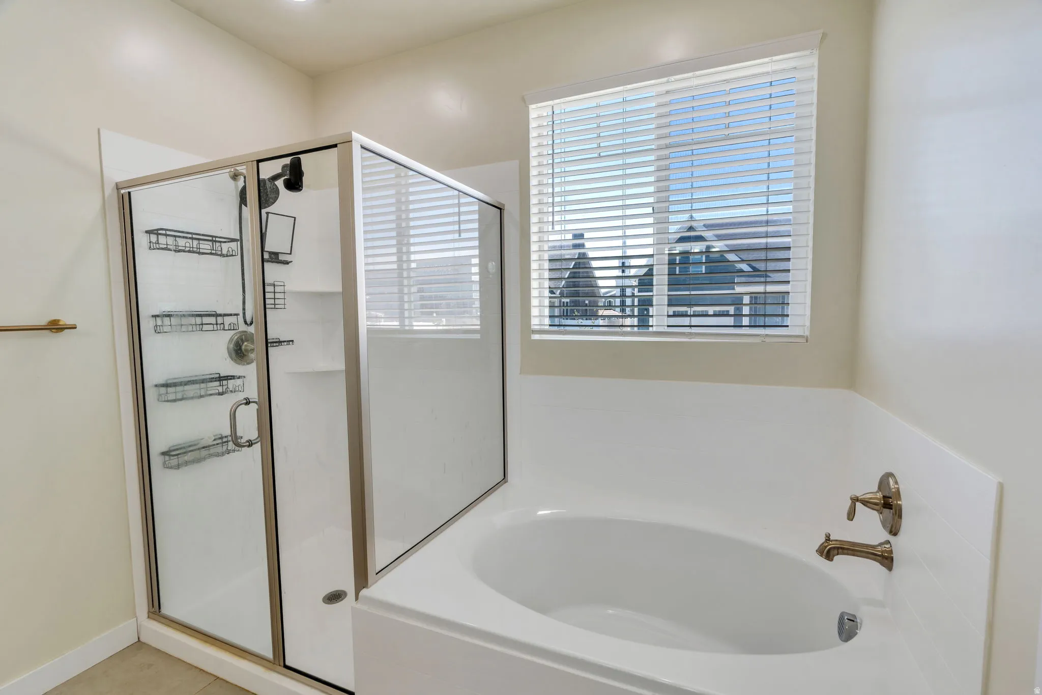 Alcove bathtub with deck-mounted bronze fixtures and an adjacent glass-enclosed shower with multiple built-in shelves