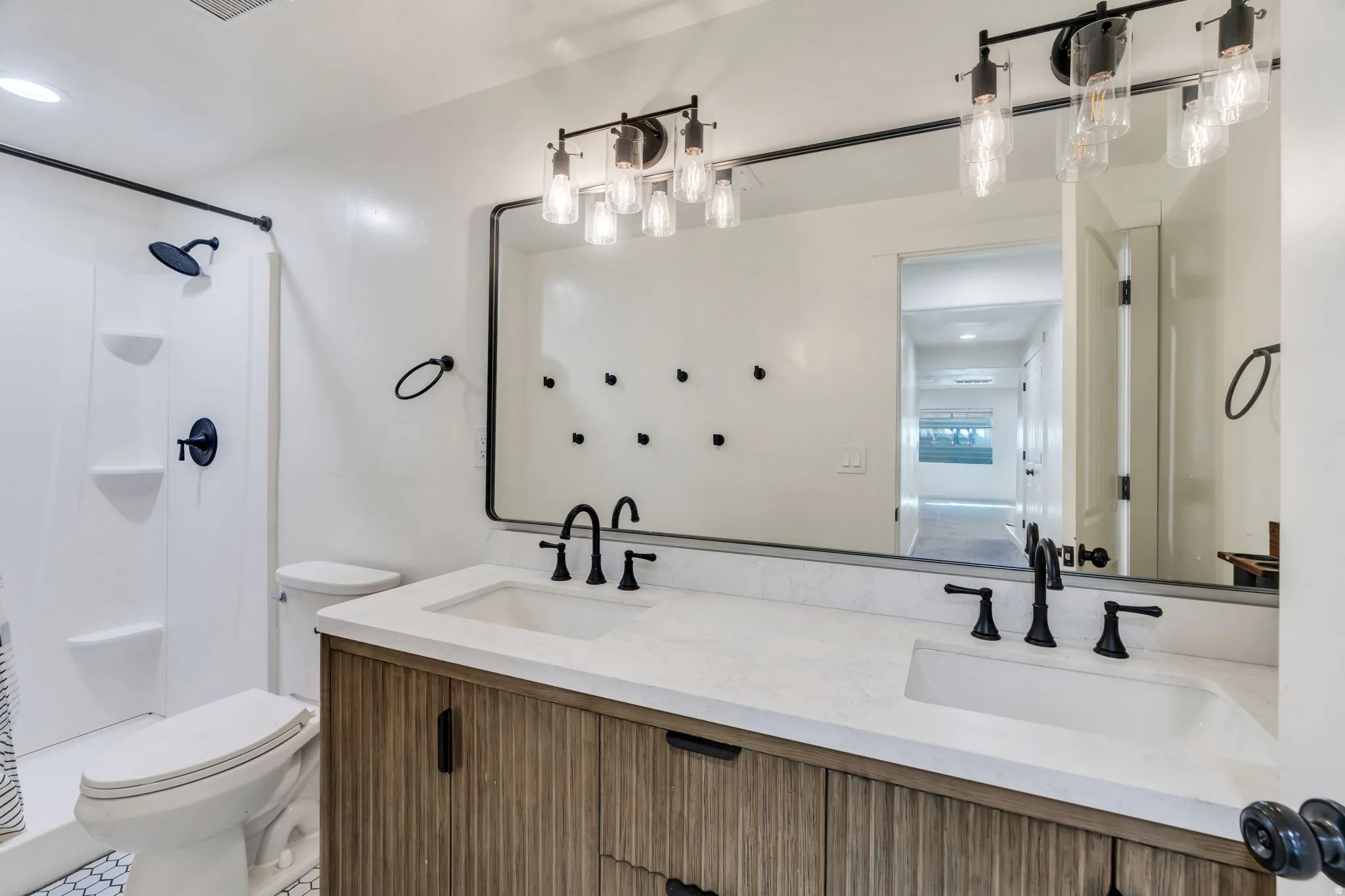 Bathroom featuring a double vanity with integrated sinks, wood-finish cabinetry, and matte black hardware