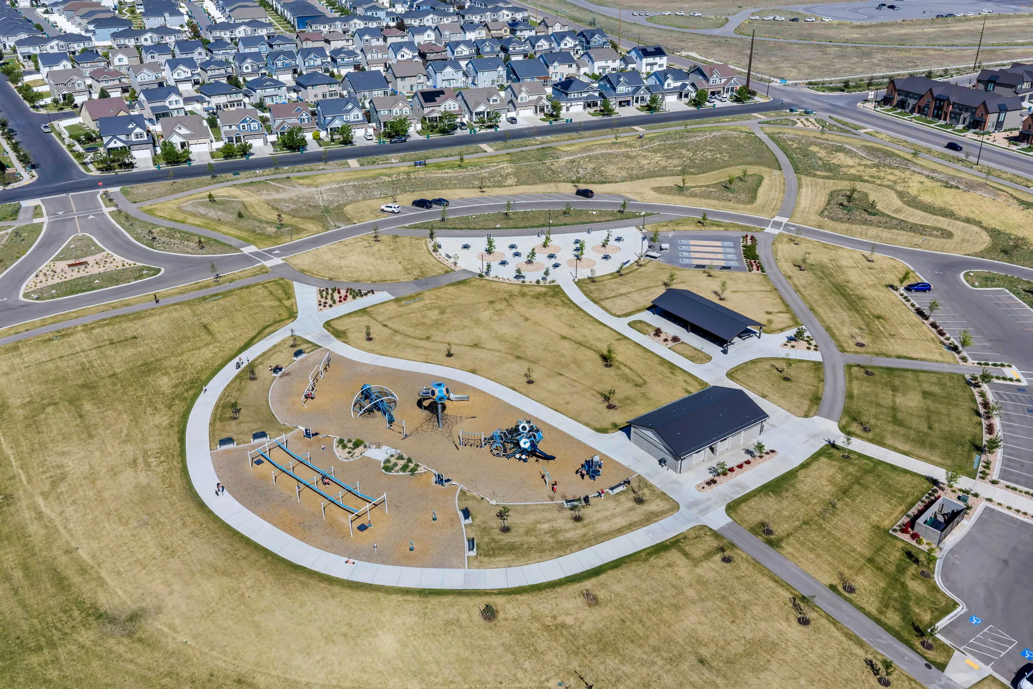 Community park featuring multiple play structures, a covered pavilion, and extensive walking paths