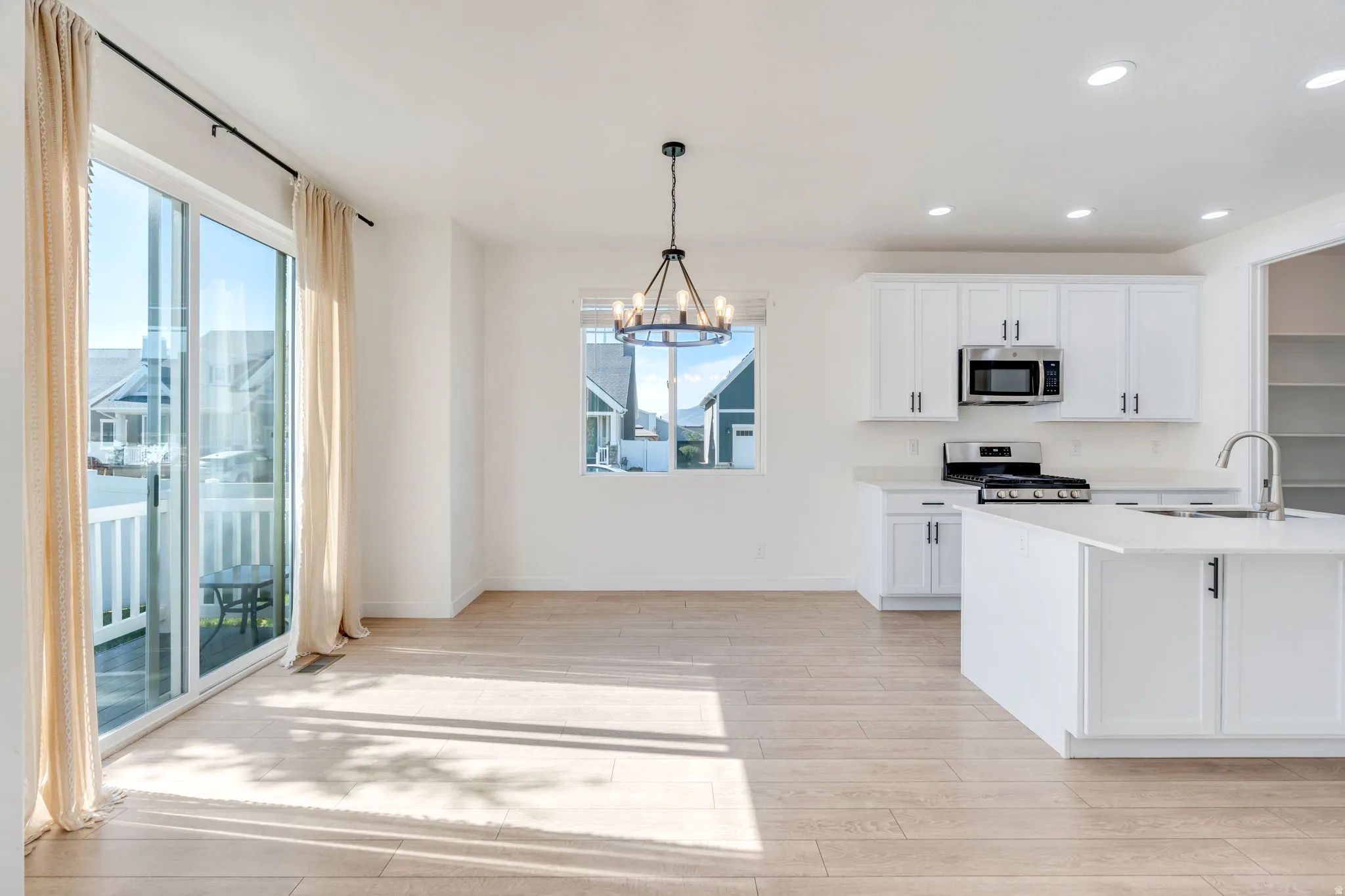 Open-concept living area featuring light wood-finish flooring, white walls, and recessed lighting