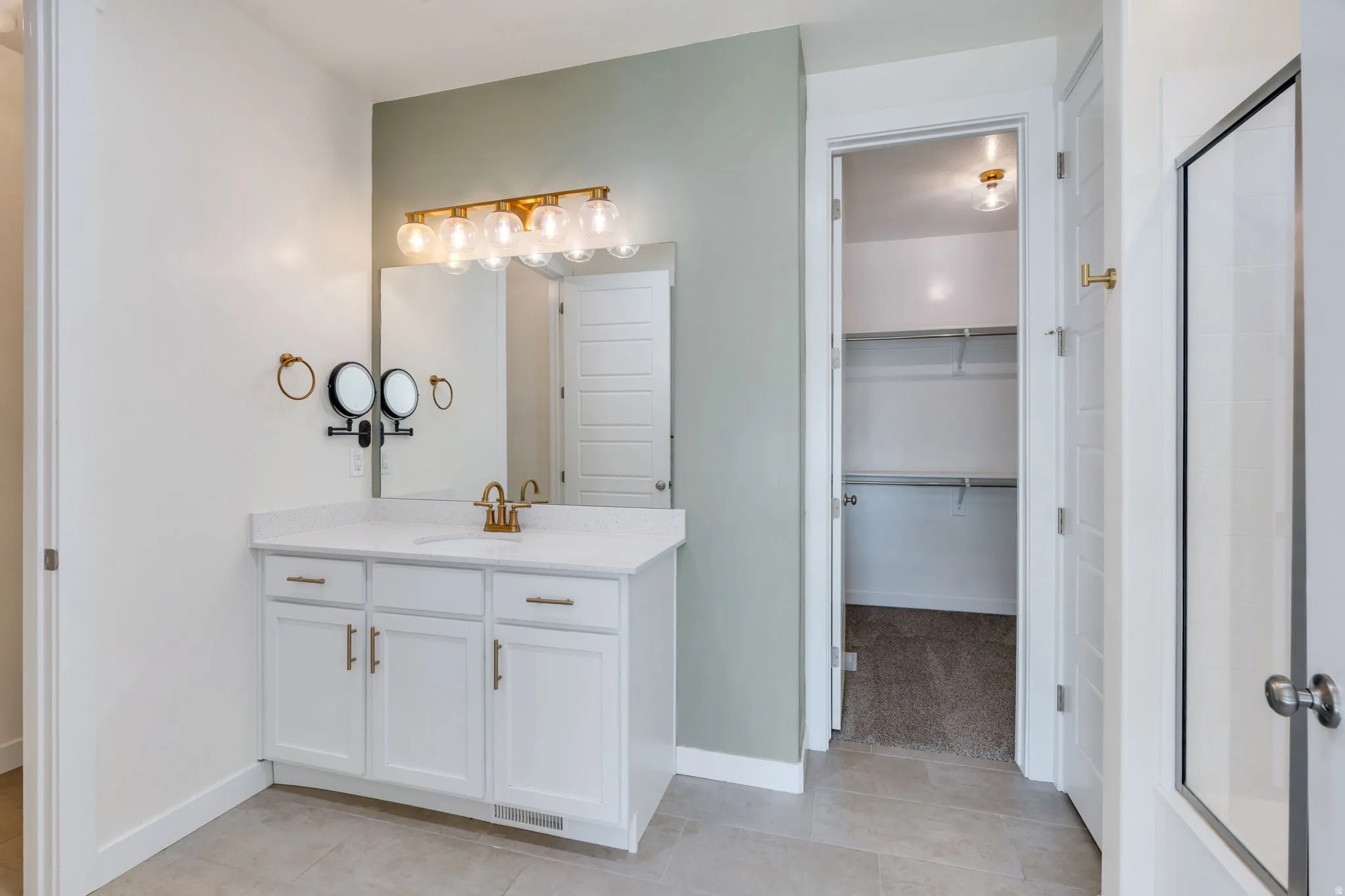 Bathroom vanity featuring a white cabinet with gold-finish hardware, a light-colored countertop, and a rectangular mirror