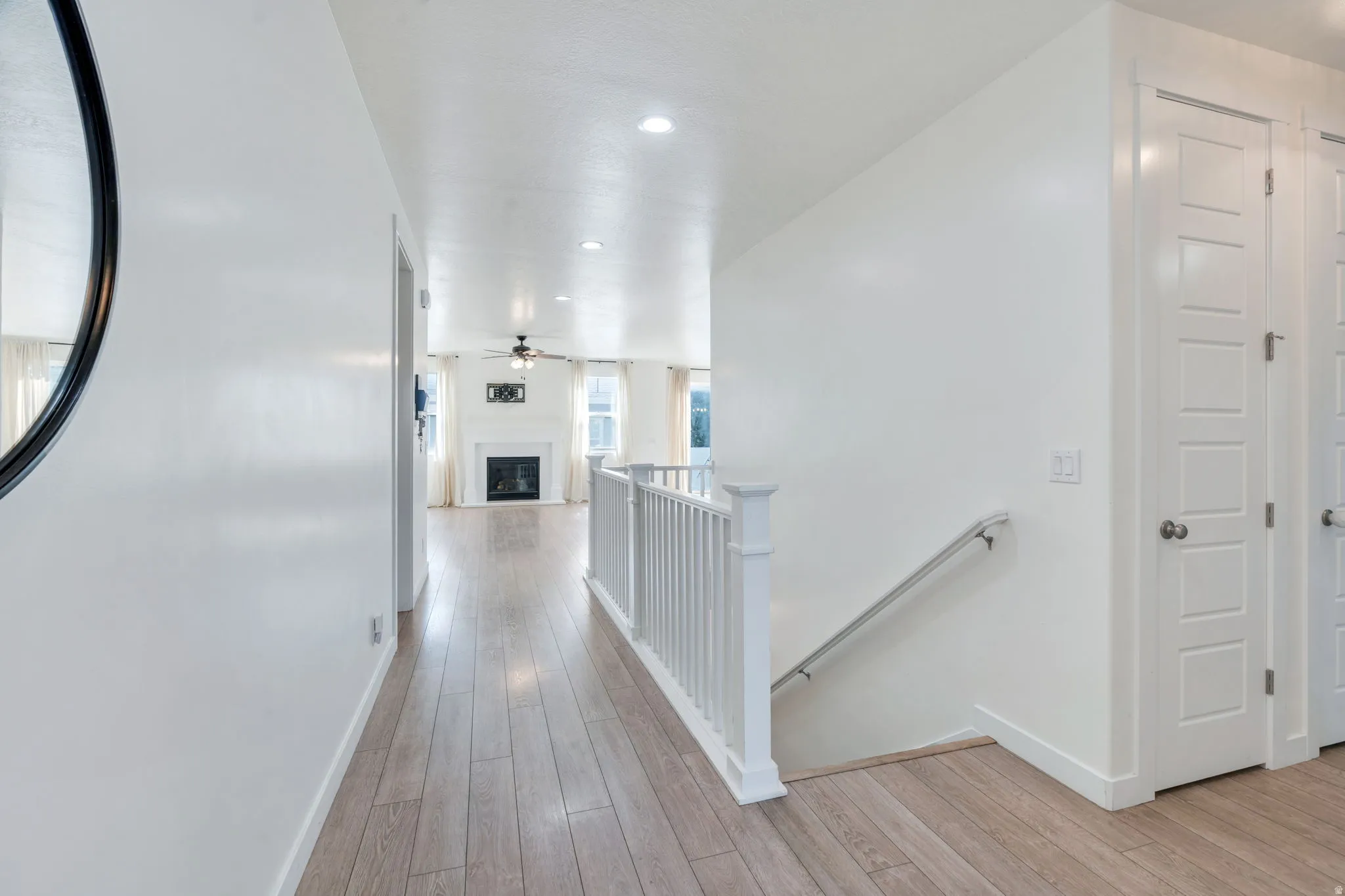 Hallway featuring wood-finish flooring, white walls, and recessed lighting