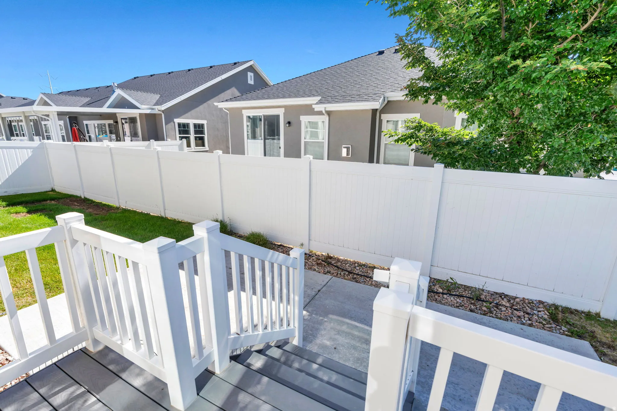 Outdoor deck with composite planking and white railings descending to a concrete patio
