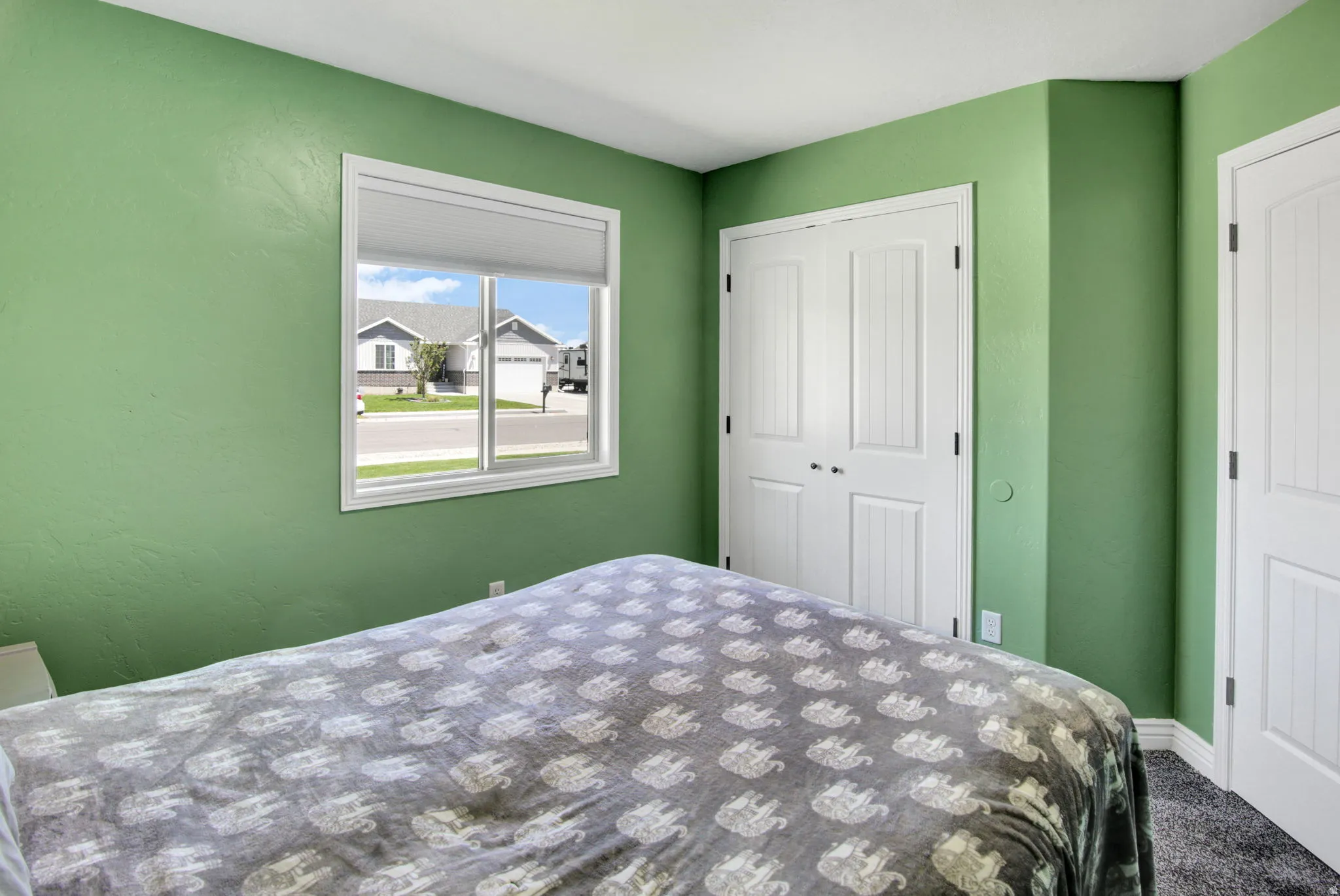 Bedroom featuring a large window, two white paneled bi-fold closet doors, and textured wall finish