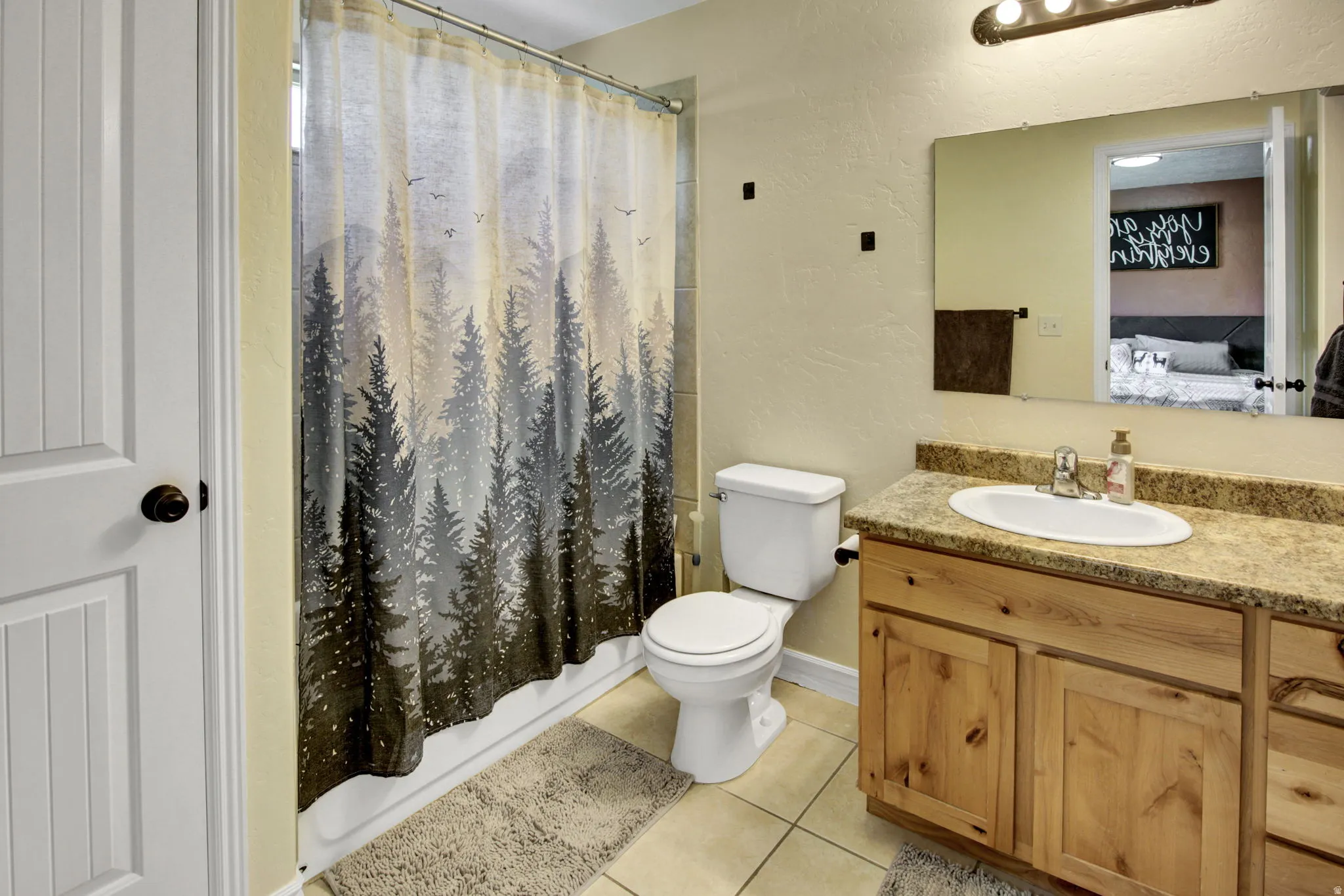 Bathroom featuring a built-in wood vanity with a light-toned countertop, an oval undermount sink, and chrome fixtures