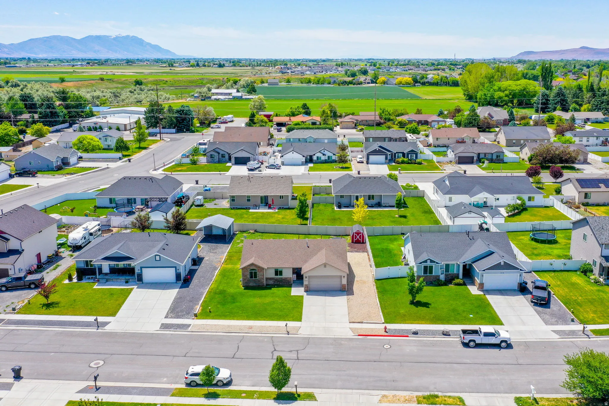 Aerial perspective of a residential neighborhood featuring single-story homes with manicured lawns and paved driveways
