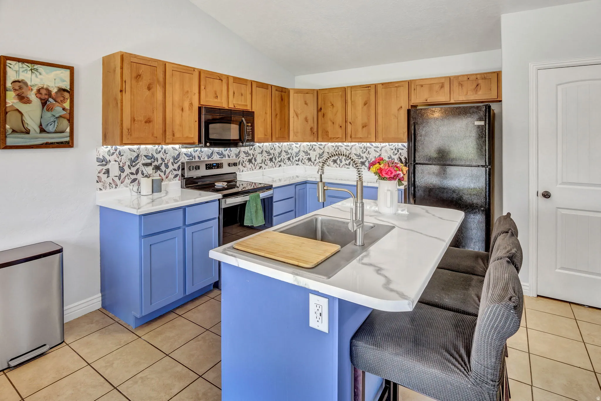 Kitchen featuring light wood-finish upper cabinetry, periwinkle lower cabinetry, and white countertops with gray veining