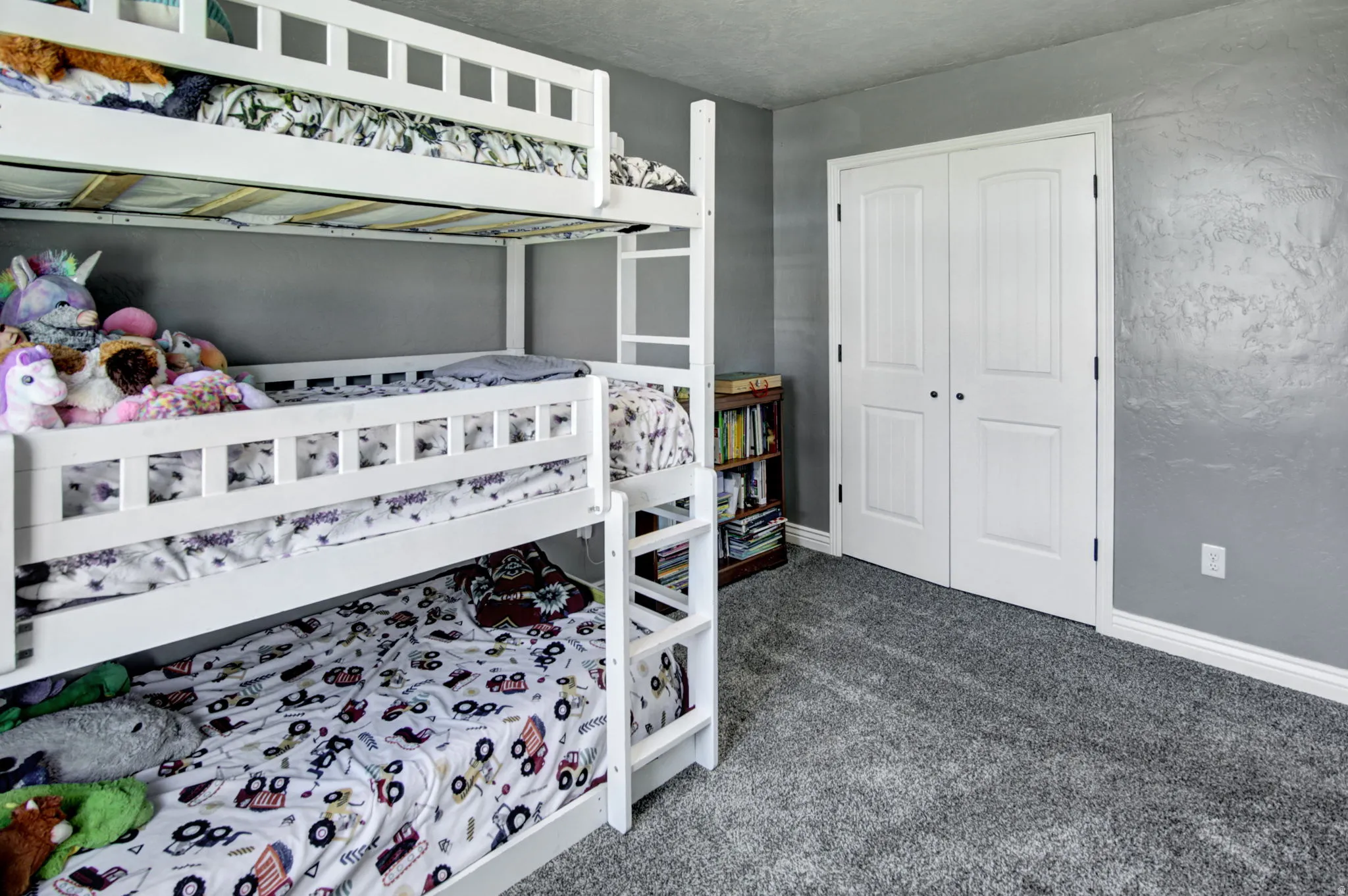 Room featuring textured gray walls, white trim, and gray carpet flooring