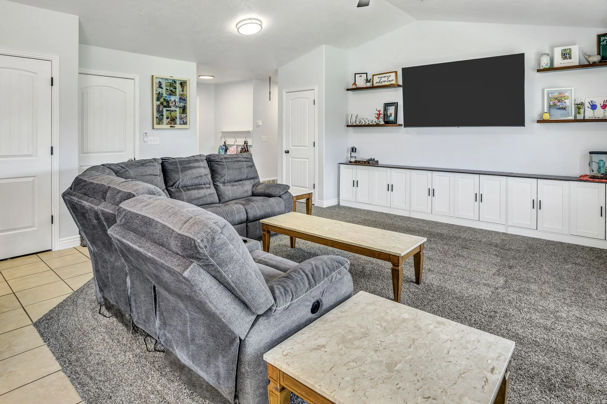 Spacious living area featuring light-toned walls and vaulted ceilings