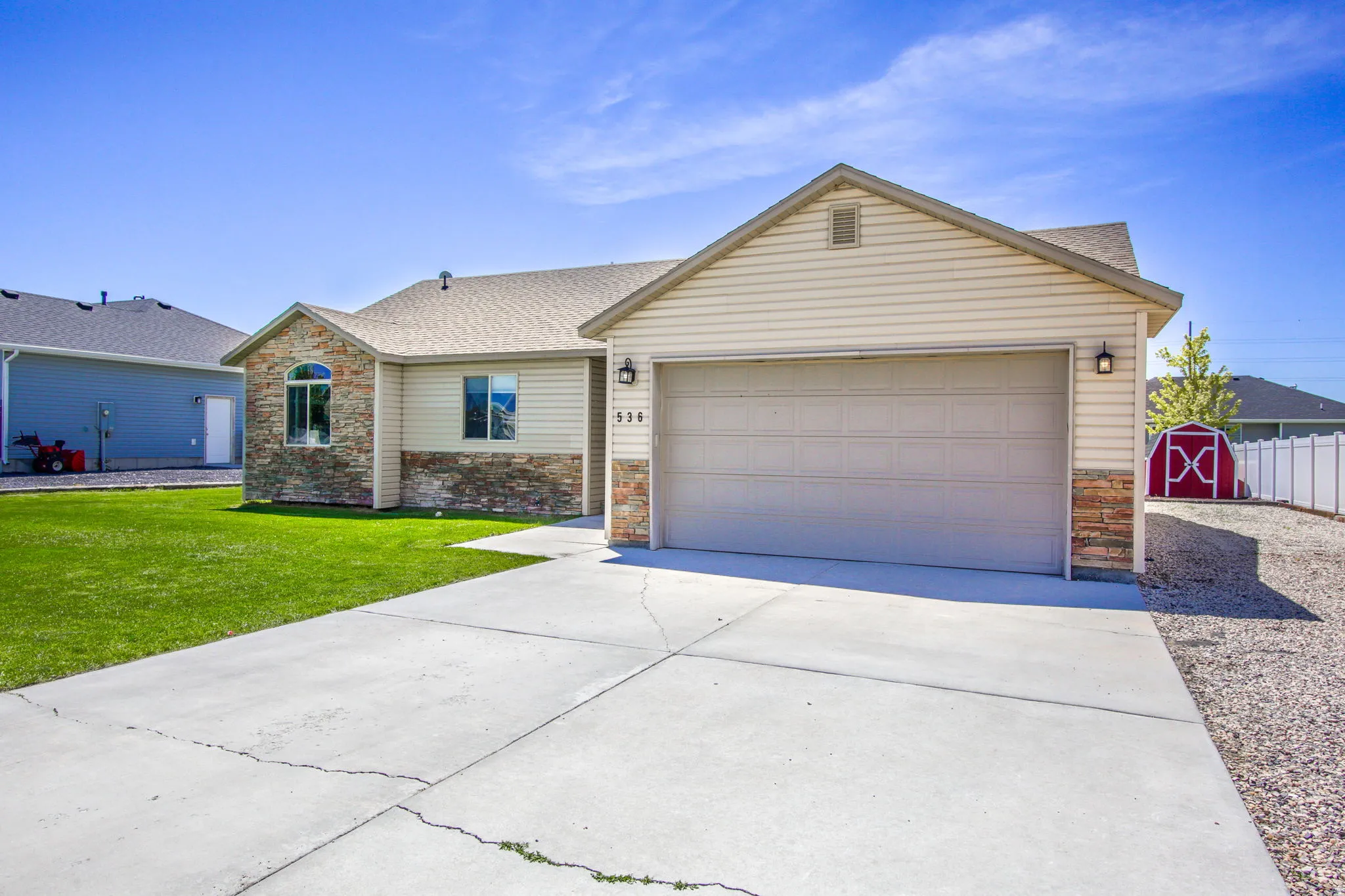 Single-story residence featuring a concrete driveway, an attached garage, and stone veneer accents