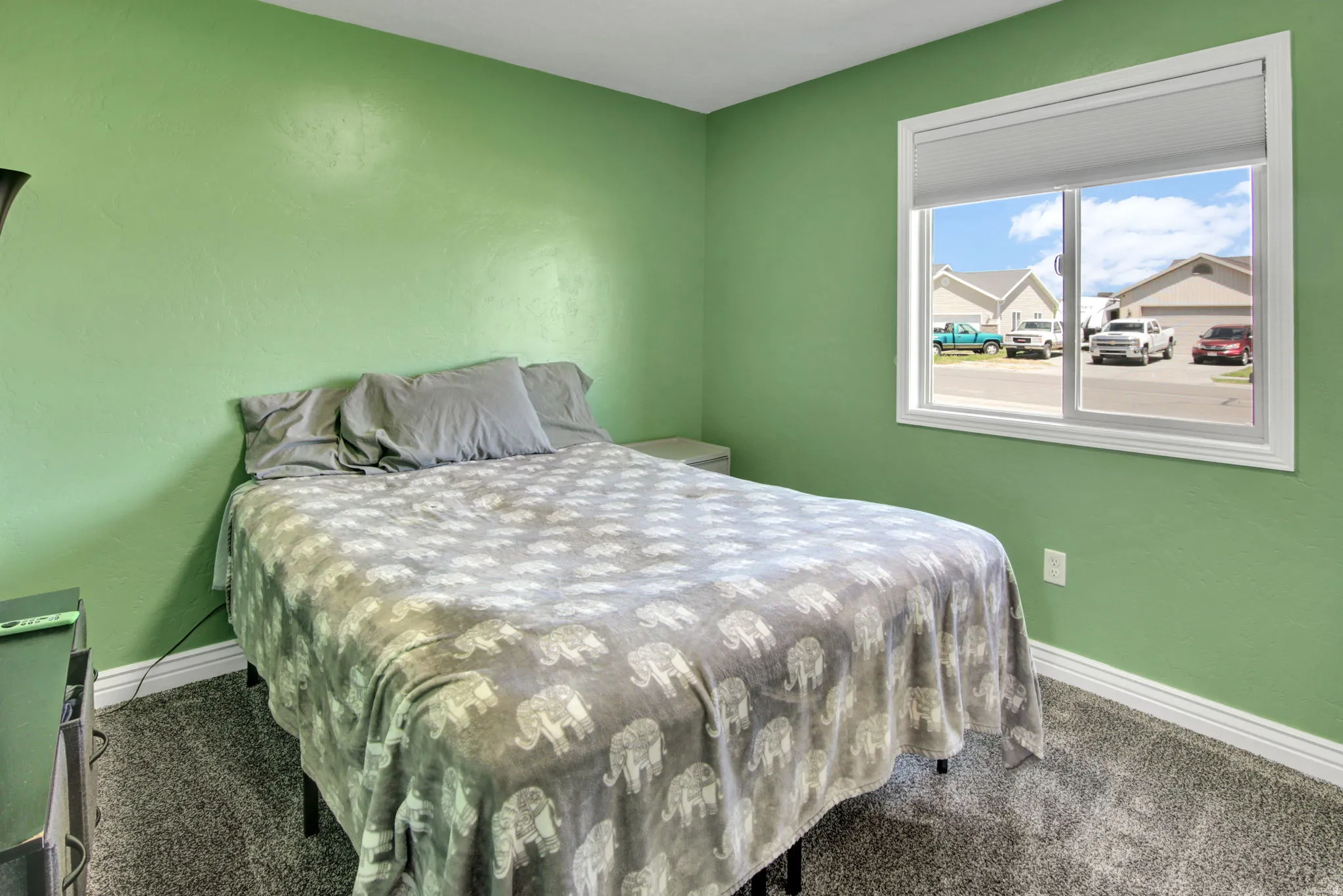 Carpeted room featuring a white-framed window with integrated blinds, light green walls, and white baseboards