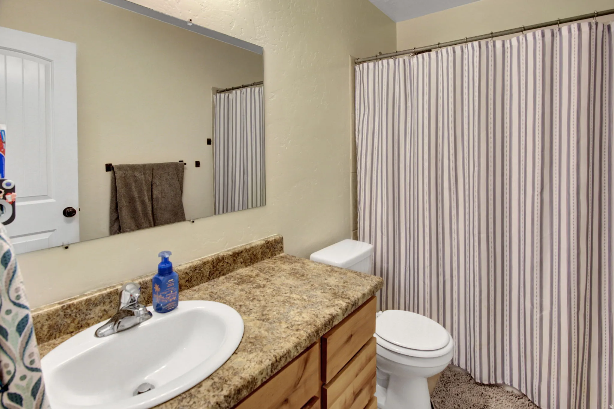 Bathroom with a wood-finish vanity, light-toned countertop, and an undermount sink with a chrome faucet