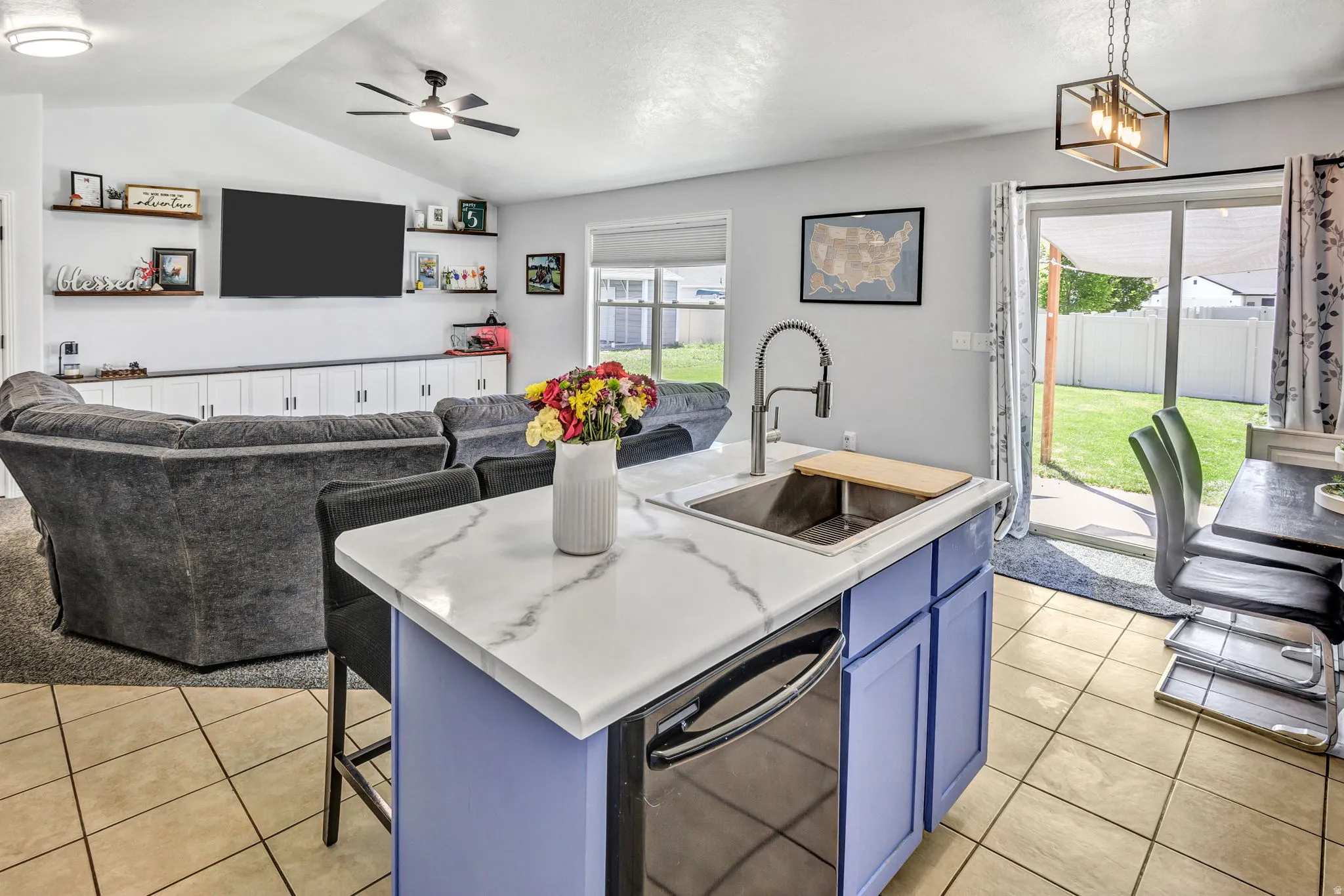 Kitchen island with a light-toned countertop, integrated sink, and dishwasher, featuring blue cabinetry