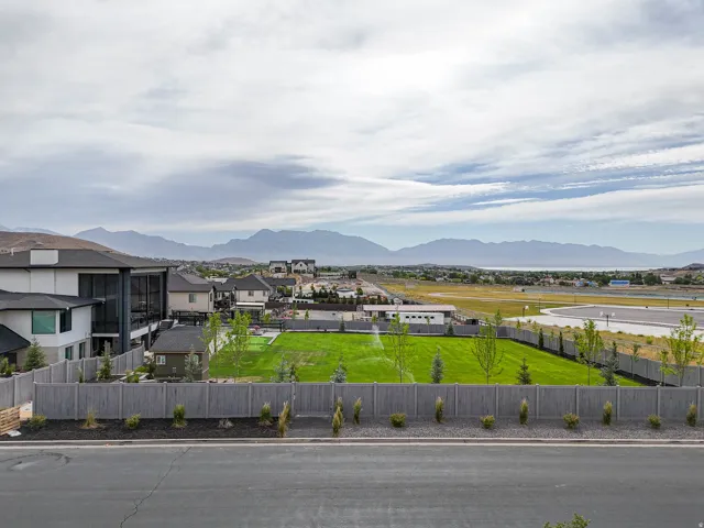 Expansive green space featuring a wooden privacy fence, mature trees, and mountain scenery