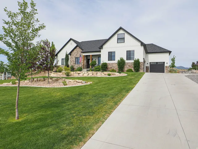 Contemporary facade featuring white vertical siding, stone accents, and dark trim windows