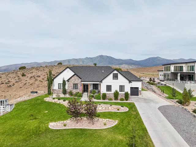 Contemporary ranch-style residence featuring a dark shingle roof, white siding, and stone accents
