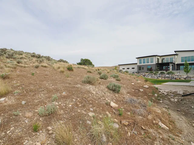 Expansive sloped property featuring natural scrub brush and scattered rocks