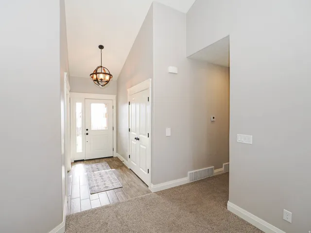 Entryway featuring a vaulted ceiling and an orb chandelier