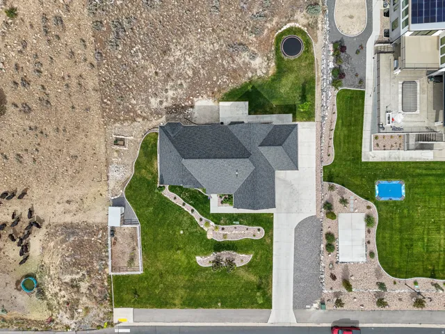 Residential property featuring a dark shingle roof, concrete driveway, and expansive green lawn