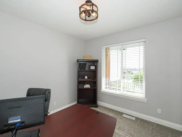 Room featuring a large window with white blinds, neutral wall paint, and a built-in dark wood-finish bookcase