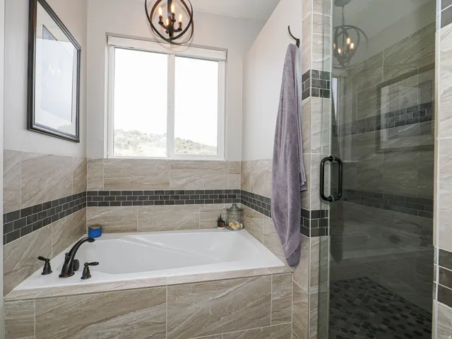 Contemporary bathroom featuring a built-in soaking tub with dark bronze fixtures, a tiled surround, and an adjacent walk-in shower with a glass enclosure