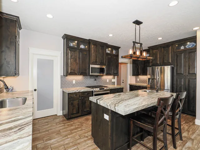 Gourmet kitchen featuring dark wood cabinetry, stainless steel appliances, and a large central island with seating