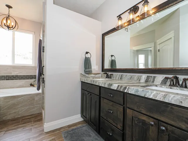 Bathroom featuring a dual vanity with dark wood cabinetry, a large framed mirror, and a three-light fixture