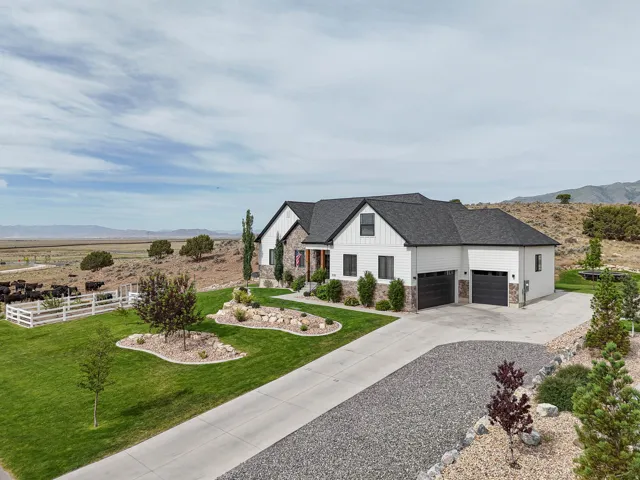 Modern farmhouse-style exterior featuring white siding, dark trim, and a stone accent foundation