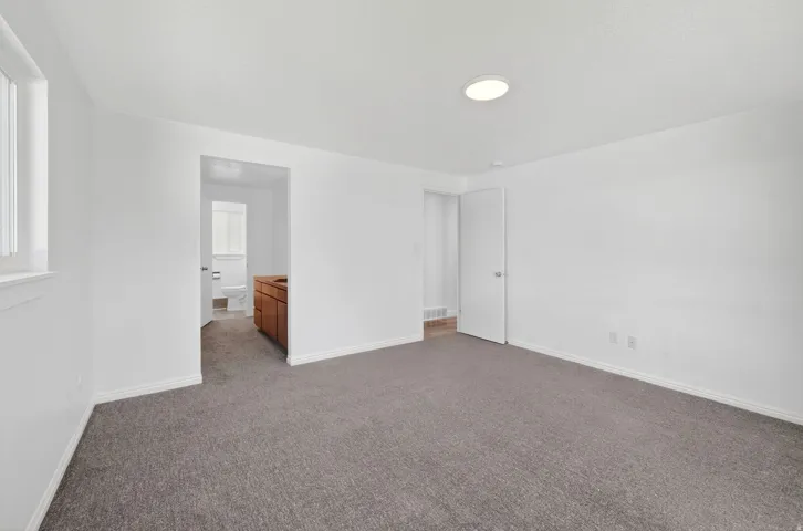 Spacious room with new gray carpet, white walls, and a large window