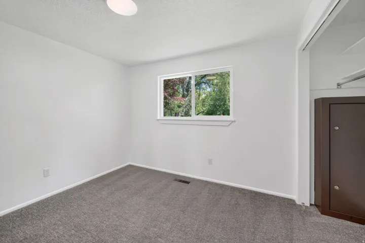 Bedroom featuring neutral-toned walls, gray carpeting, and a window with exterior views