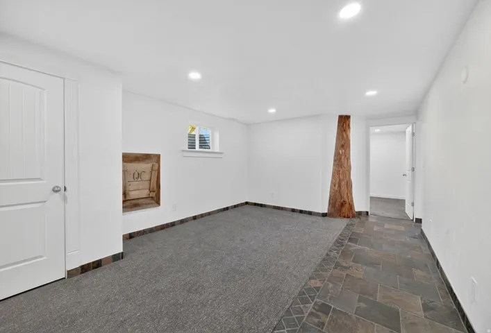 Spacious room featuring recessed lighting, a window with louvered shutters, and a unique wood architectural element