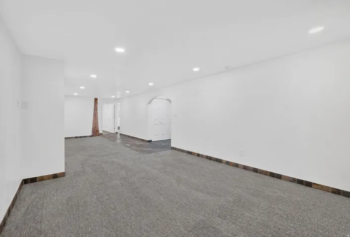 Spacious interior featuring recessed lighting, white walls, and a combination of gray carpeting and dark tile flooring