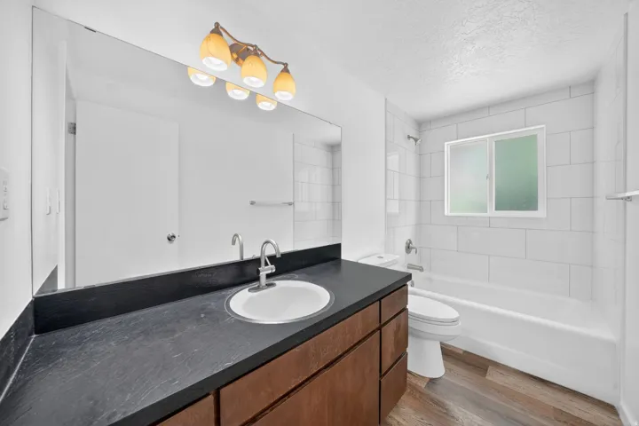 Main Level Bathroom featuring a wide vanity mirror, a dark countertop, an undermount sink, and a wood-finish vanity with drawers