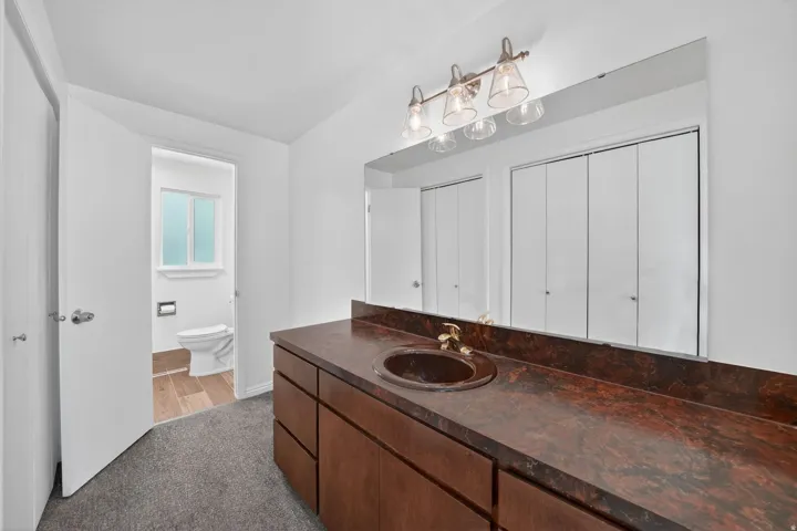 Priamary Bathroom vanity featuring an integrated sink, broad mirror, and warm wood-finish cabinetry