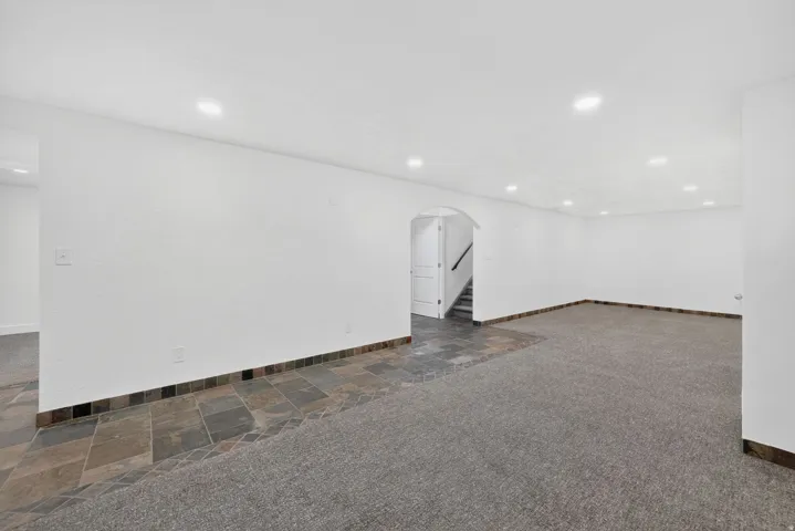 Spacious room featuring recessed lighting, a combination of carpet and slate tile flooring, and white walls