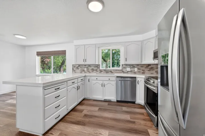 Modern kitchen featuring white cabinetry, a large center island with a light-toned countertop, and stainless steel appliances