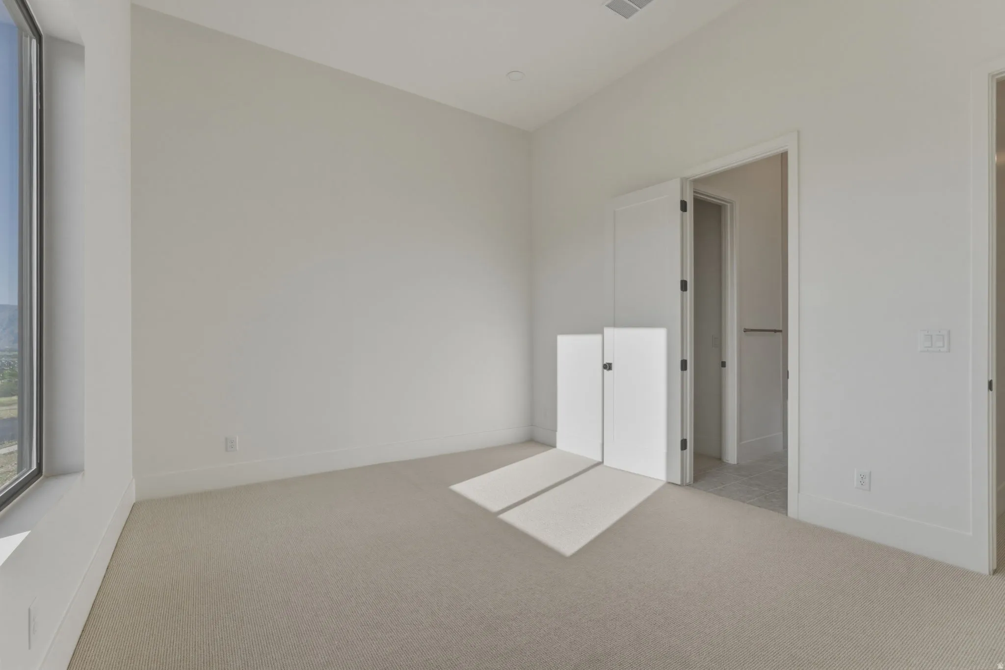 Neutral-toned carpeting extends throughout this room featuring a large window
