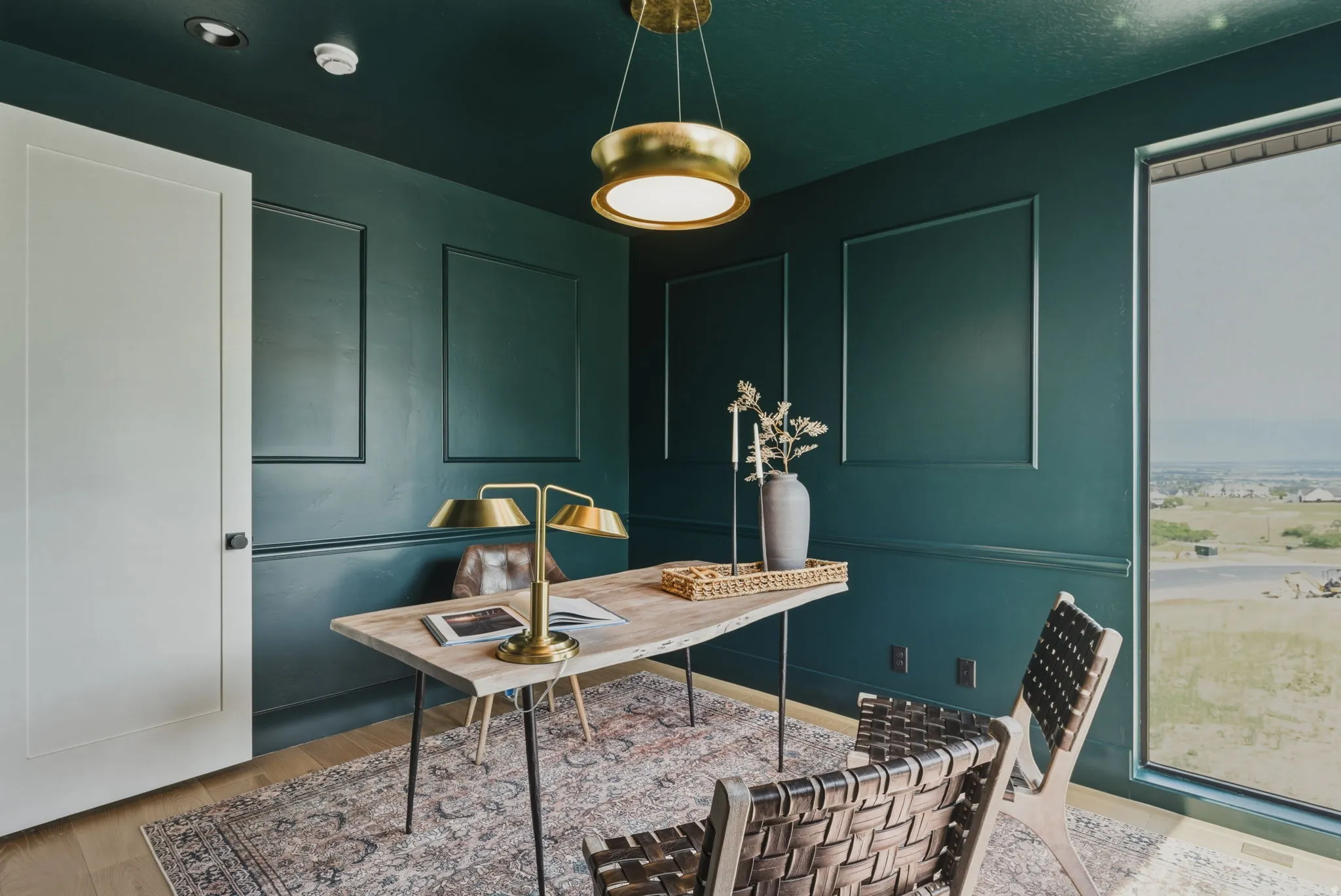Room with deep green walls featuring decorative wall molding and a large window