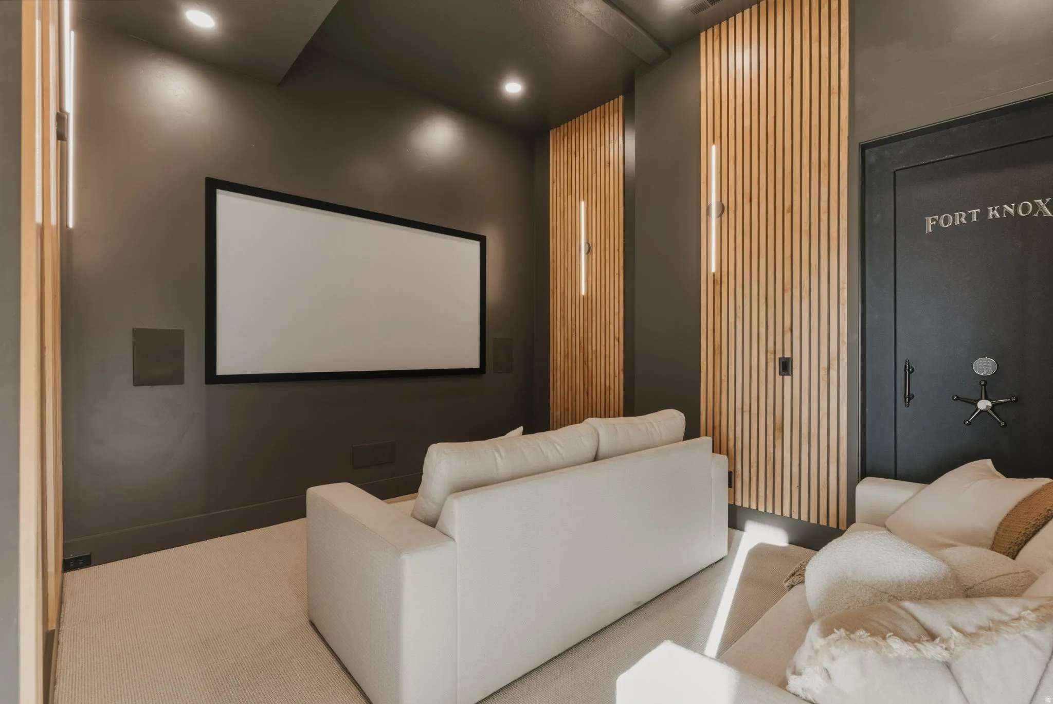 Dedicated media room featuring a large projection screen, recessed ceiling lighting, and integrated wall speakers
