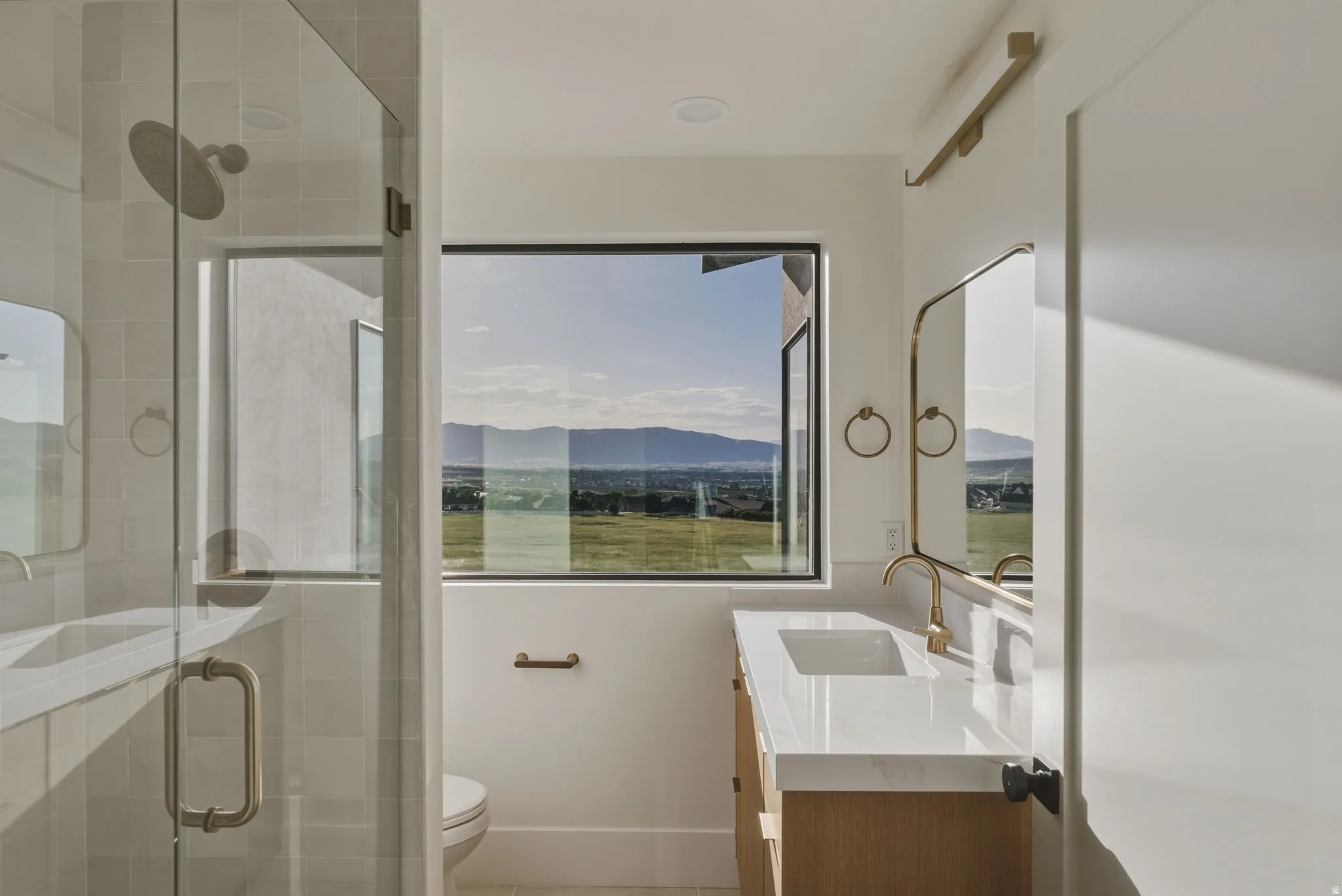 Modern bathroom featuring a large picture window with mountain and landscape scenery