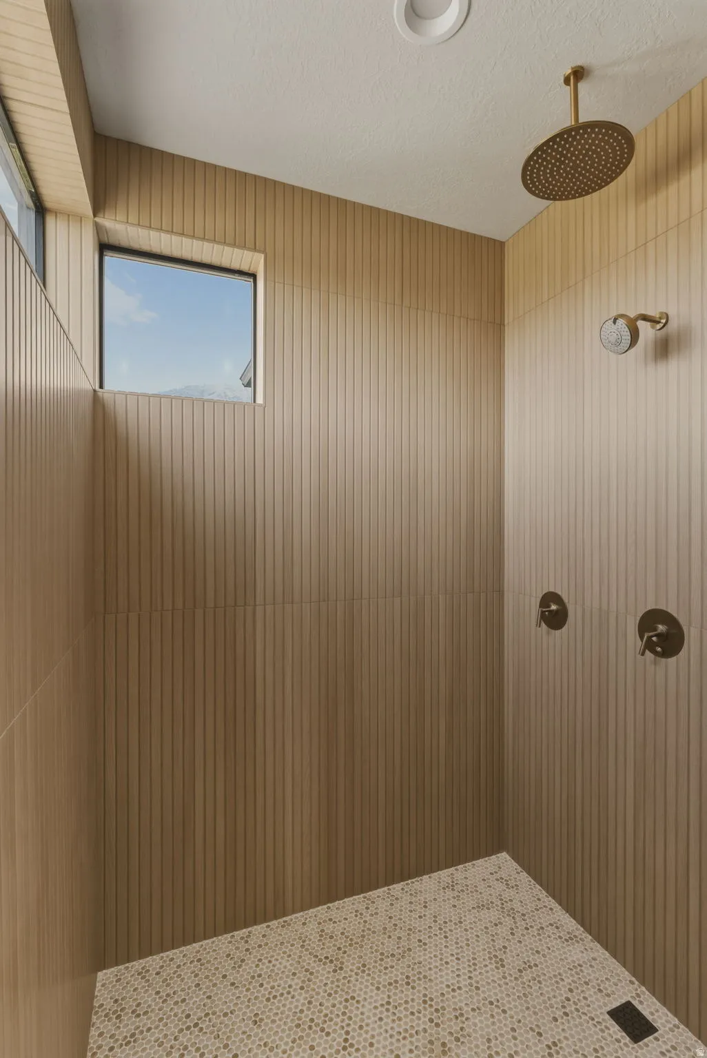Spacious shower enclosure with wood-finish vertical slat wall paneling, dual brass shower heads, and an integrated bench seating area
