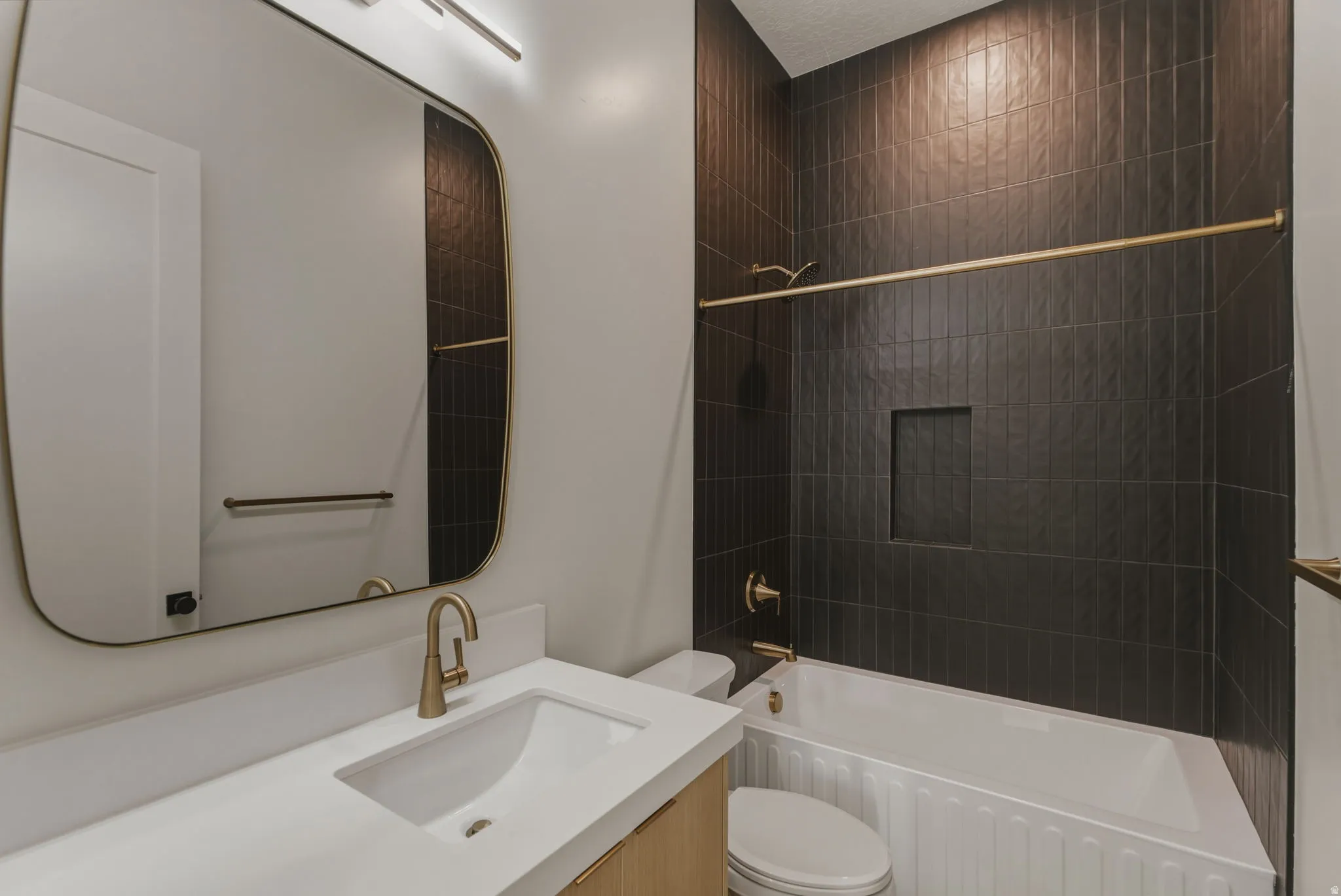 Bathroom featuring a built-in tub with dark vertical tile surround and recessed shelving