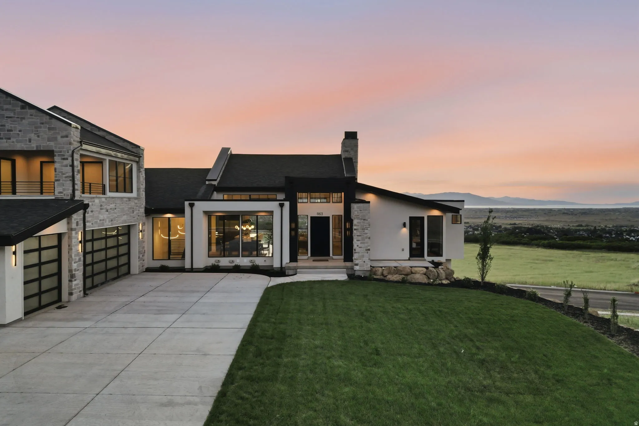 Contemporary exterior featuring a stone and stucco facade, a concrete driveway, and full-view garage doors