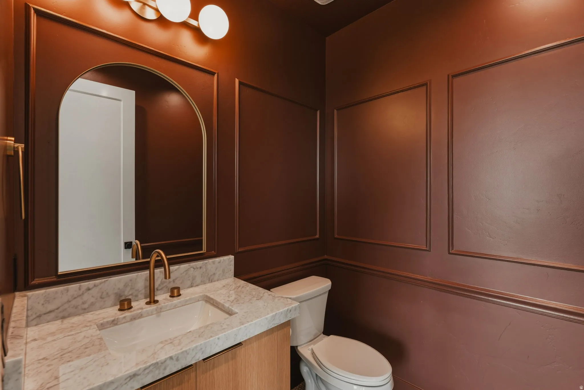 Powder room featuring a wood-finish vanity with an undermount sink and a light-toned countertop