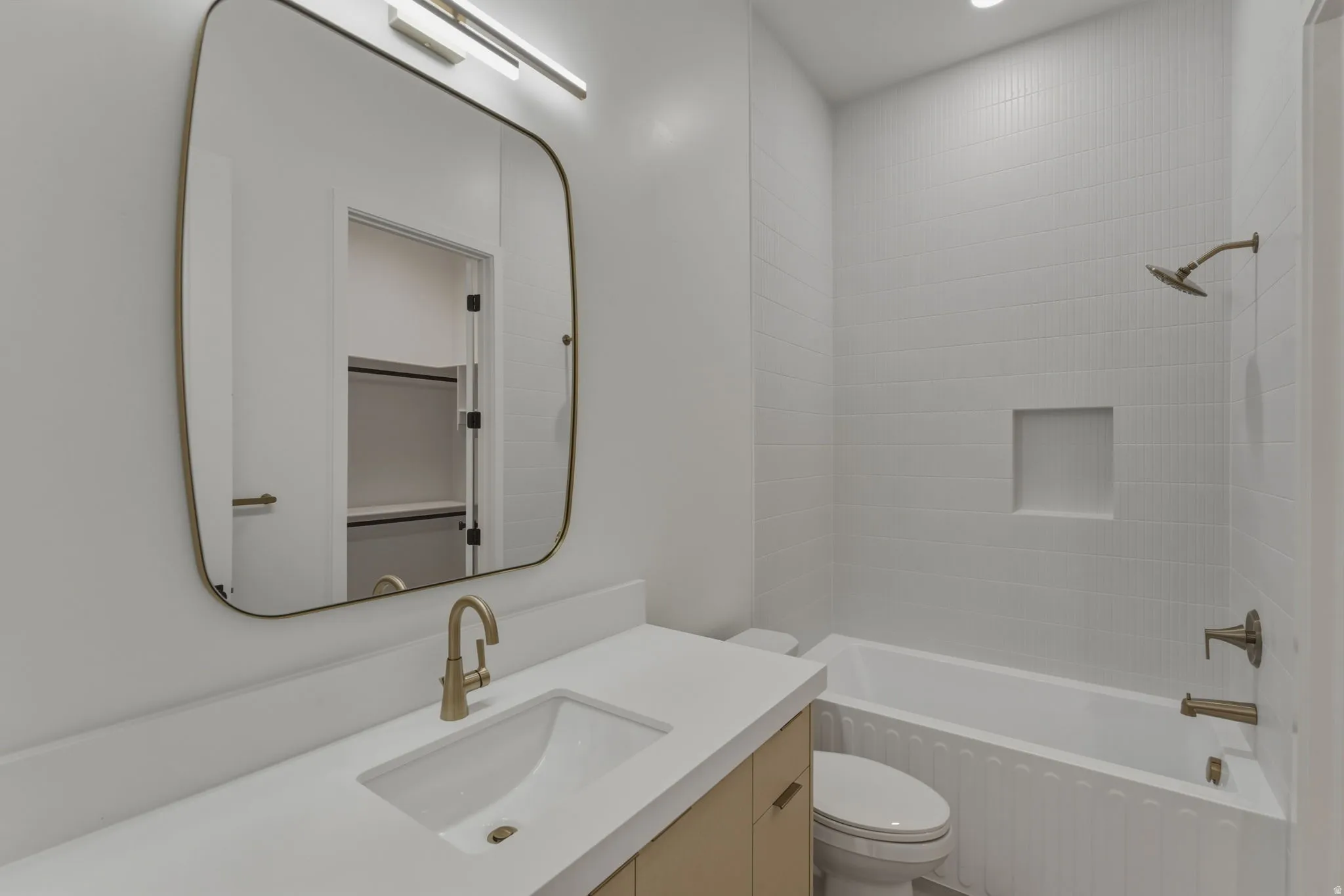 Bathroom featuring a single vanity with stone countertop, undermount sink, and brass-finish faucet